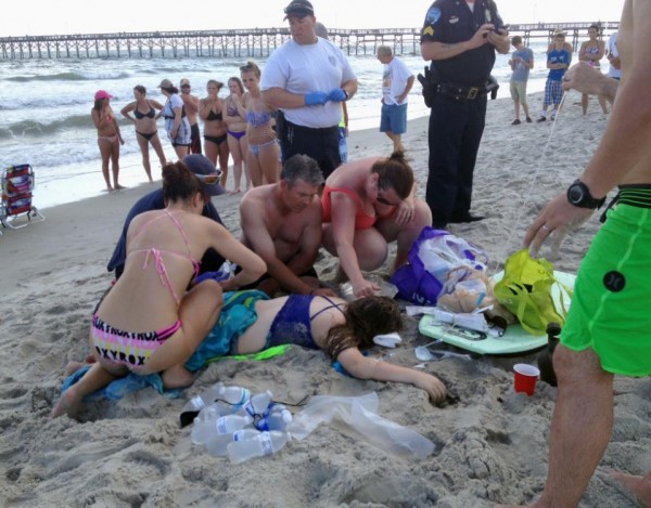 Emergency responders assist a teenage girl at the scene of a shark attack in Oak Island, N.C., Sunday, June 14, 2015. Mayor Betty Wallace of Oak Island, a seaside town bordered to the south by the Atlantic Ocean, said that hours after the teenage girl suffered severe injuries in a shark attack Sunday a teenage boy was also severely injured. (Steve Bouser/The Pilot, Southern Pines, N.C. via AP) MANDATORY CREDIT