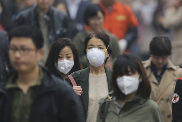 People wearing masks walk along a street on a heavy hazy day in Beijing, March 27, 2014. REUTERS/Jason Lee (CHINA - Tags: ENVIRONMENT)