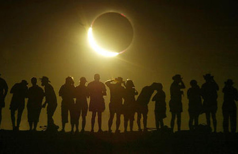 Tourists watch the sun being blocked by the moon during a solar eclipse in the Australian outback town of Lyndhurst, located around 700 kilometres (437 miles) north of Adelaide December 4, 2002. The town is one of only four in Australia where the 26 second-long full eclipse of the sun could be seen and occurred during celebrations for the Year of the Outback. The shadow path of whats called totality, where the 'diamond ring' effect becomes visible, can be seen on a path that is just 36 kilometres wide.           REUTERS/David Gray