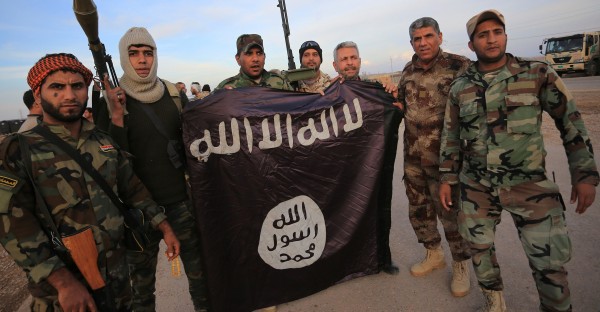 Iraqi Shi'ite fighters pose with an Islamic State flag which they pulled down on the front line in Jalawla, Diyala province, November 23, 2014. Iraqi forces said on Sunday they retook two towns north of Baghdad from Islamic State fighters, driving them from strongholds they had held for months and clearing a main road from the capital to Iran. Picture taken November 23, 2014. REUTERS/Stringer (IRAQ - Tags: CIVIL UNREST POLITICS CONFLICT MILITARY TPX IMAGES OF THE DAY) - RTR4FAVG