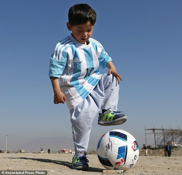 FILE - In this Friday, Feb. 26, 2016 file photo, Murtaza Ahmadi, a five-year-old Afghan Lionel Messi fan plays with a soccer ball during a photo opportunity as he wears a shirt signed by Messi, in Kabul, Afghanistan. The father of Ahmadi says the family was forced to leave Afghanistan amid constant telephone threats. (AP Photo/Rahmat Gul, File)